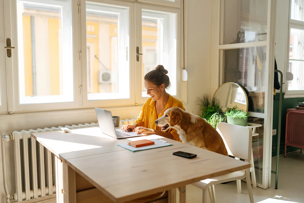 Woman working aat a desk with her dog beside her