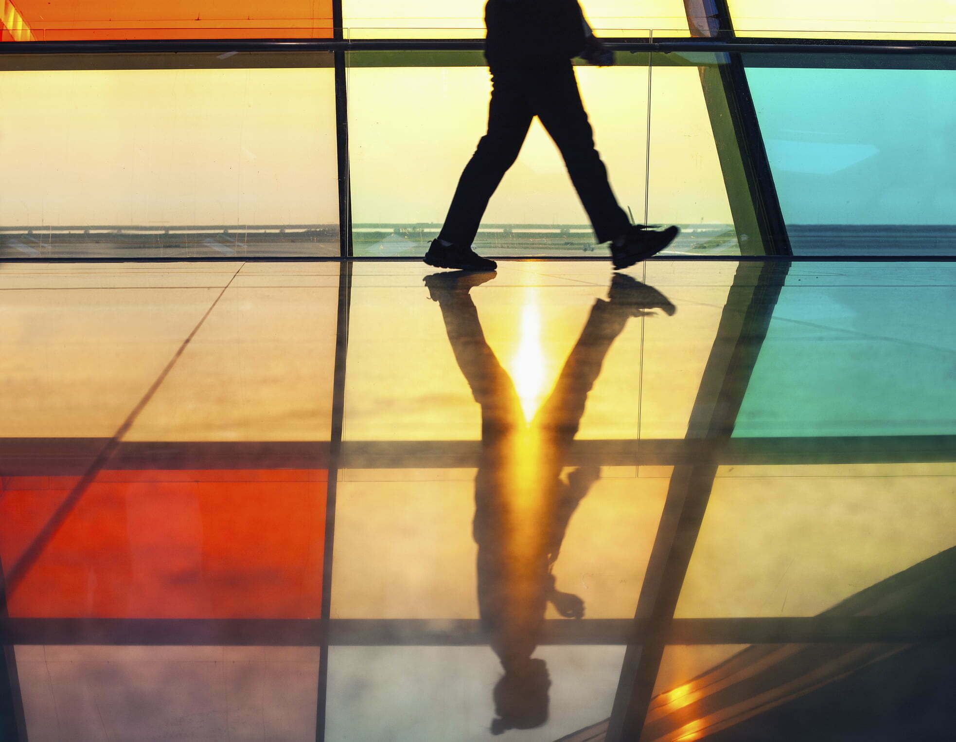 Low angle view of person walking through back lit corridor